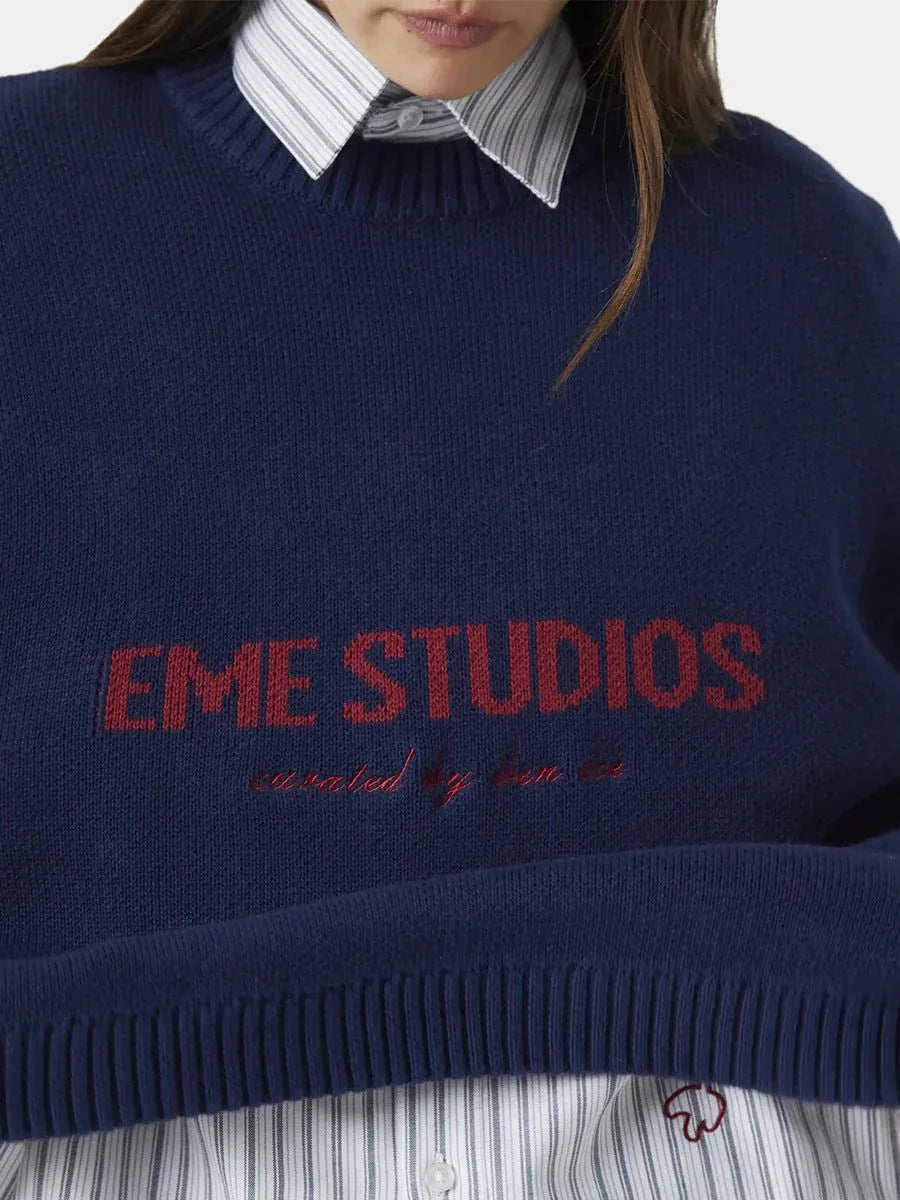 Close-up of the navy blue crewneck sweater with red embroidered logo.