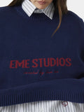 Close-up of the navy blue crewneck sweater with red embroidered logo.