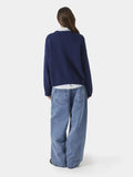 Back view of a woman wearing a navy blue crewneck sweater and wide-leg jeans.