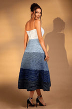 Back view of a woman in a white and blue ombre textured midi dress with a sweetheart neckline and spaghetti straps.