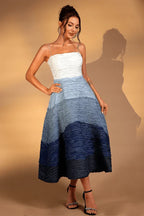 Side view of a woman wearing a white and blue ombre textured midi dress with a sweetheart neckline.