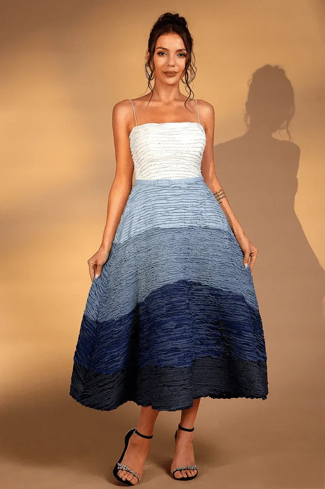 Woman wearing a white and blue ombre textured midi dress with spaghetti straps and side pockets.