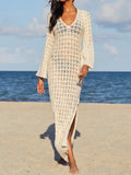 Woman wearing a cream crochet knit maxi dress with bell sleeves and a V-neck on a beach