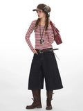 Full body shot of a woman styled with a striped top, culottes, belt, and hat