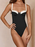 Woman in black and white one-piece swimsuit, front view