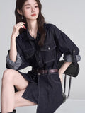 Woman wearing a dark wash denim shirt dress with a brown belt and silver star earrings.