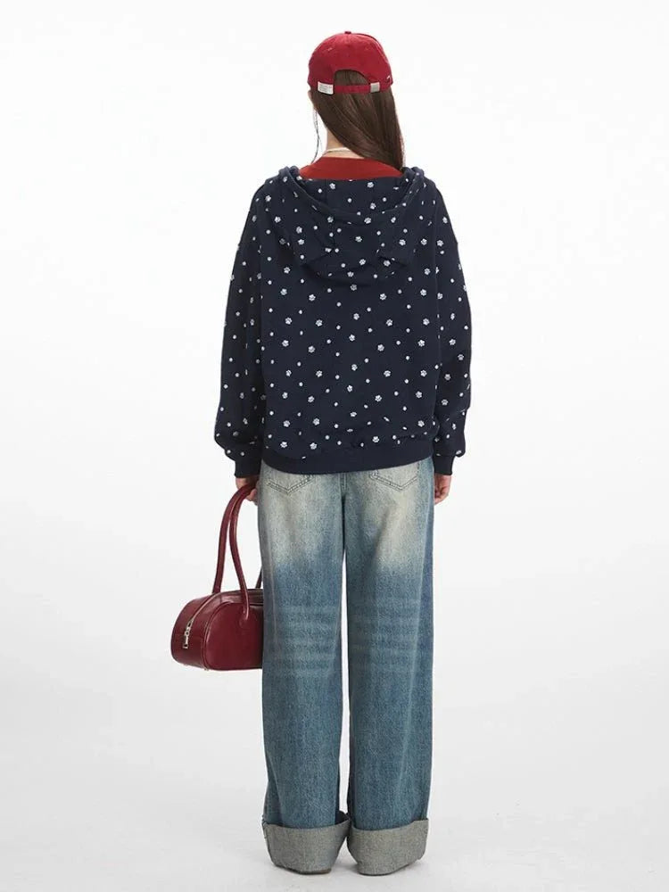 Back view of a woman wearing a navy blue zip-up hoodie with a white paw print pattern