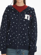 Detailed view of the chest area of a navy blue zip-up hoodie with a paw print pattern and embroidered graphic