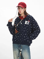 Close-up of a woman wearing a navy blue zip-up hoodie with a white paw print pattern and an embroidered graphic