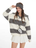 Close-up of a woman wearing a grey and white striped knit sweater with a spread collar and zipper closure, accessorized with a headband and a small circular bag.