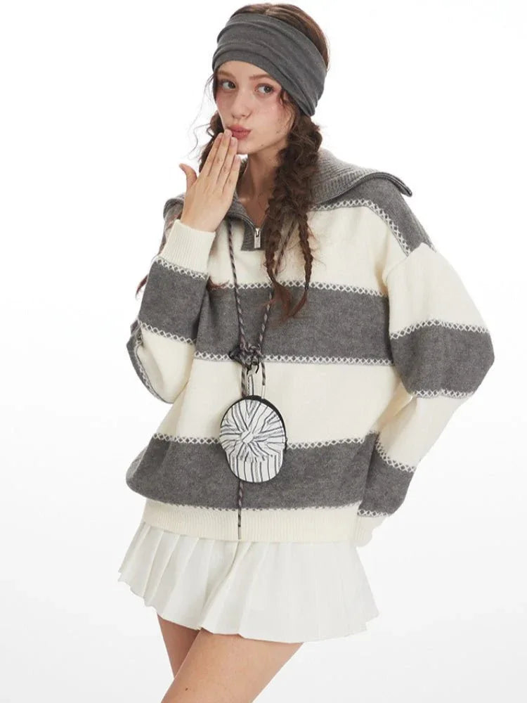 Woman posing in a grey and white striped knit sweater with a spread collar and zipper closure.