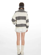 Back view of a woman wearing a grey and white striped knit sweater with a spread collar and zipper closure.