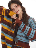 Close-up of a woman's face and upper body, highlighting the striped knit cardigan with her arm resting on her cheek.