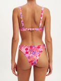 Back view of a woman wearing a pink floral print bikini, showing the clasp closure and adjustable straps.