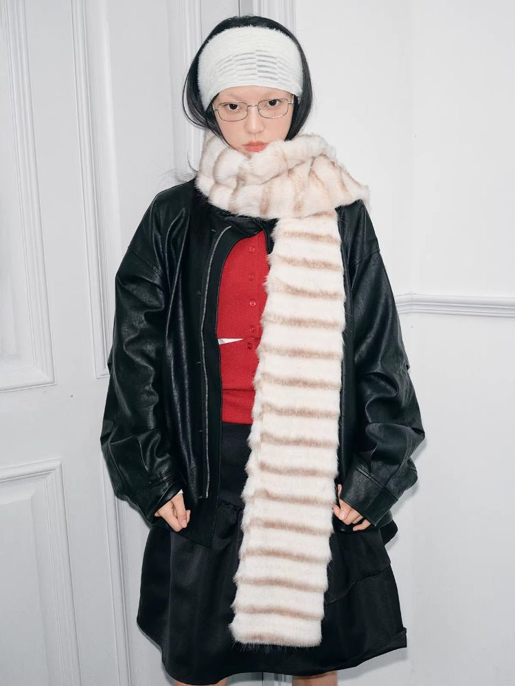 Front view of a model styled with a striped faux fur scarf and a black jacket.