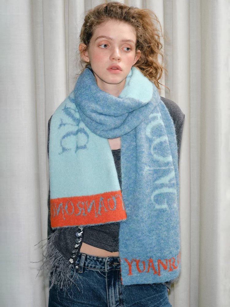 Model wearing a blue and light blue knit scarf with orange trim and graphic text.