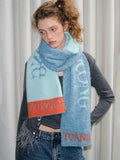Model wearing a blue and light blue knit scarf with orange trim and graphic text.