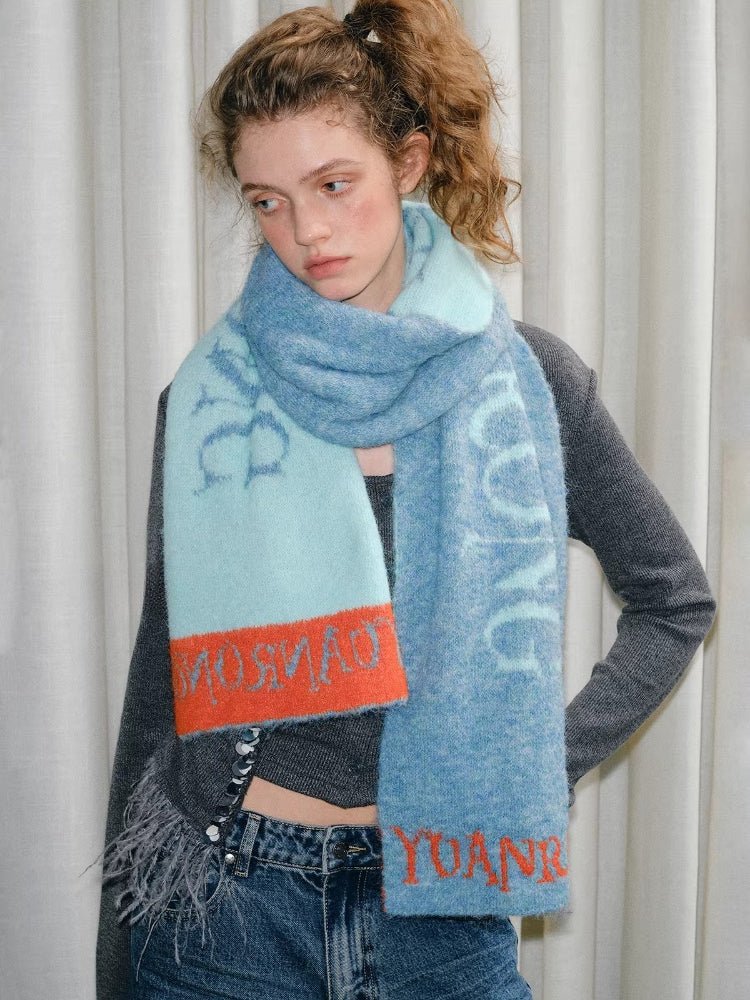 Model wearing a blue and light blue knit scarf with orange trim and graphic text.