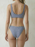 Back view of a woman wearing a blue and white striped bikini with a scoop neck and racerback top