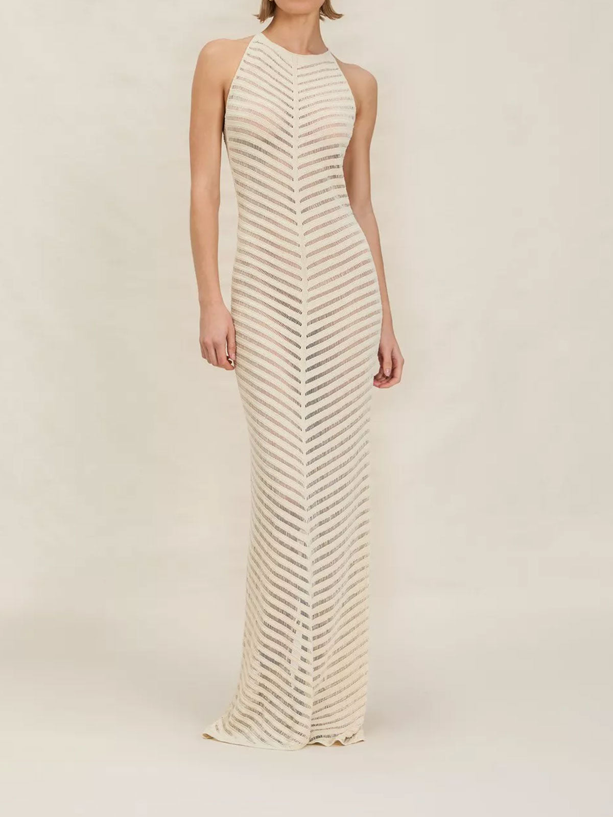 Woman wearing an ivory knit maxi dress with a halter neckline and chevron pattern