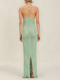 Back view of a woman in a mint green knit maxi dress with an open back and ring details