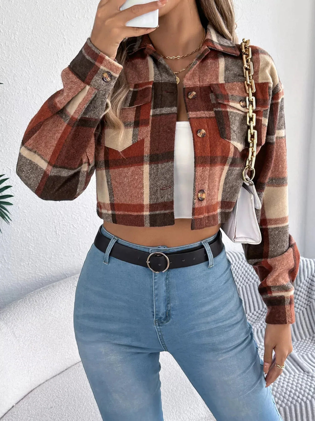 Woman styling a plaid cropped shirt jacket with a white top, blue jeans, and a white handbag