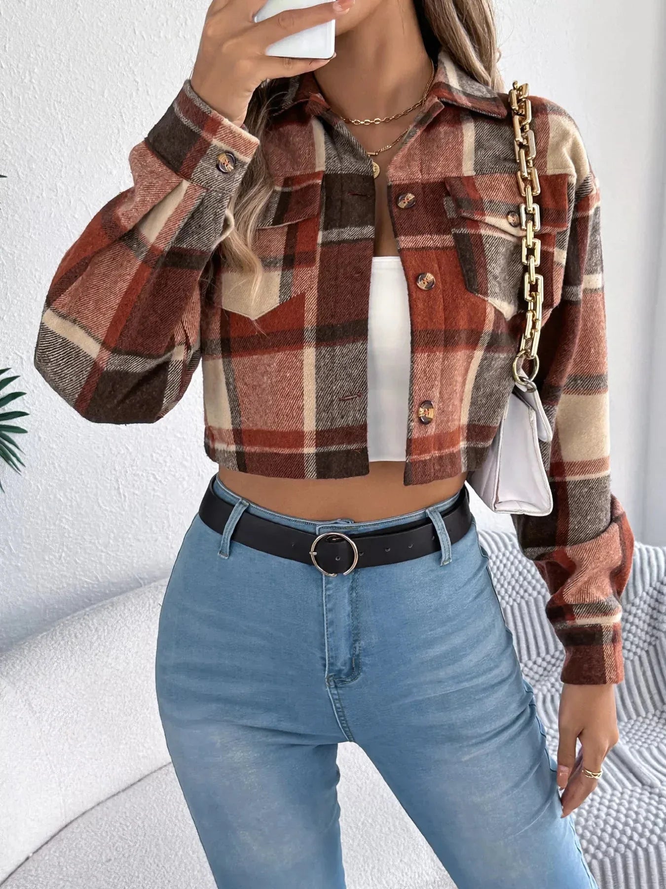 Woman styling a plaid cropped shirt jacket with a white top, blue jeans, and a white handbag