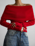 Woman in a red off-the-shoulder sweater and blue jeans.