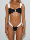 Woman wearing a black and white two-piece bikini with a twisted front top and high-cut bottoms