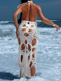 Back view of a woman wearing a long, white crochet knit dress with a backless design and cut-outs.