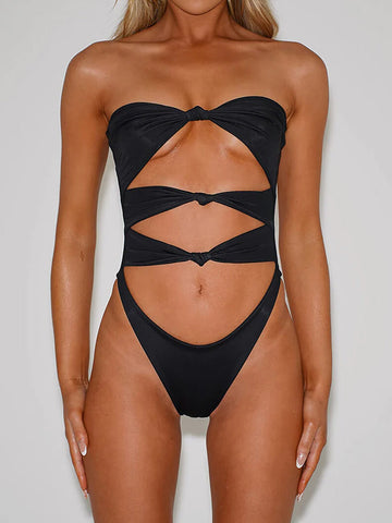 Woman wearing a black strapless one-piece swimsuit with cut-out details and twisted front