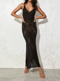 woman wearing a black sheer knit maxi dress with geometric cut-outs and a high side slit