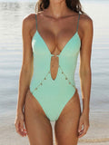 Woman wearing a mint green one-piece swimsuit with a deep V-neck and cut-out detail at the front, adorned with a gold chain belt with charms.