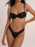 Woman wearing a black ruched bikini set with underwire bust support and adjustable straps.