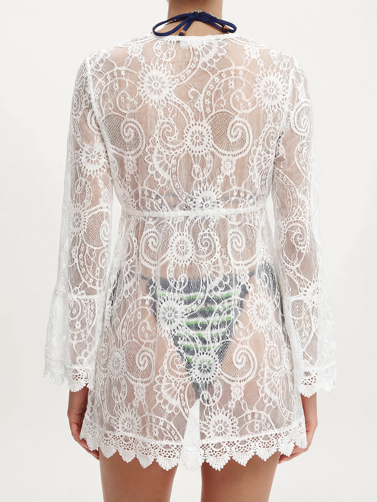 Back view of a woman wearing a white lace cover-up with bell sleeves, showing the intricate lace pattern.