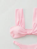 Close-up of a pink bikini top with a twisted knot detail and wide shoulder straps.