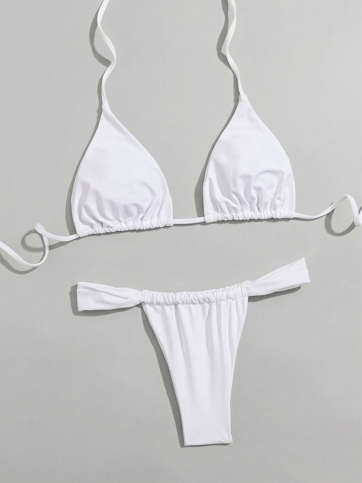 White triangle bikini top and ruched thong bottoms laid flat