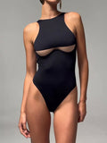 Woman wearing a black high-neck one-piece swimsuit with cut-out detail