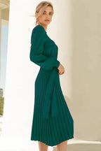 Side view of a green belted knit dress with a pleated midi skirt