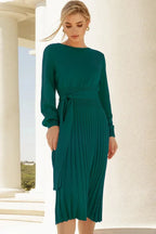 Model posing in a green knit midi dress with a tie belt