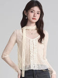 Woman wearing a cream lace long-sleeve top with ruffle front and neck scarf