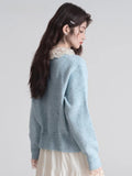 Back view of a woman wearing a light blue knit cardigan with a lace collar.
