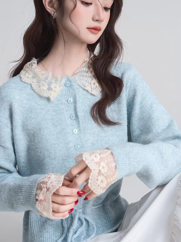 Close-up of a woman's chest wearing a light blue knit cardigan with a lace collar and lace cuffs.