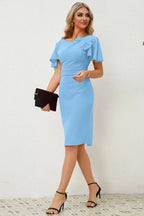 side view of a woman in a light blue pencil dress with belted waist and flutter sleeves