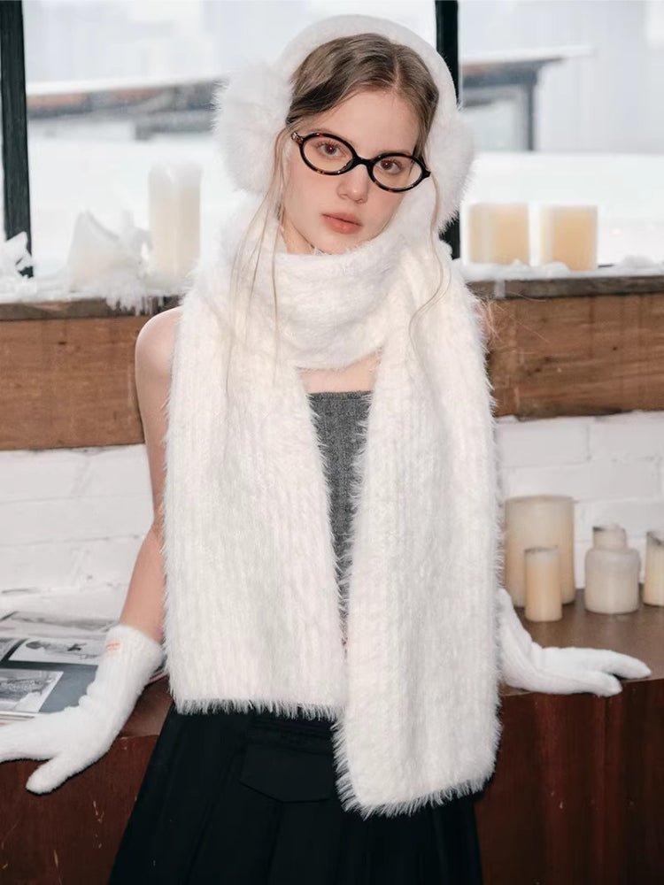 Woman wearing a white fuzzy scarf, earmuffs, and gloves