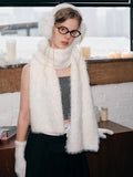 Model in white winter accessories including scarf, gloves, and earmuffs