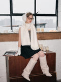 Woman sitting and modeling white winter accessories with a pleated skirt