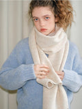 Close-up of a woman wearing a cream and beige two-tone knit scarf.