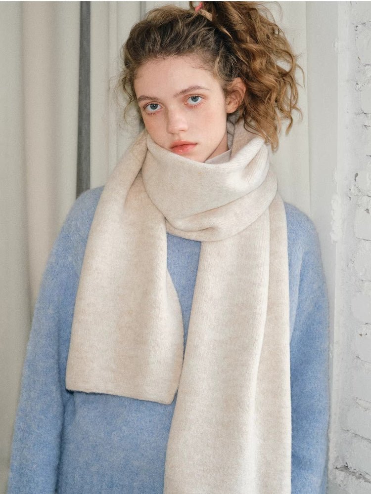 Woman in a light blue fuzzy sweater with a cream and beige knit scarf draped around her neck.