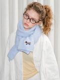 Front view of a woman accessorized with a soft, light blue winter scarf.